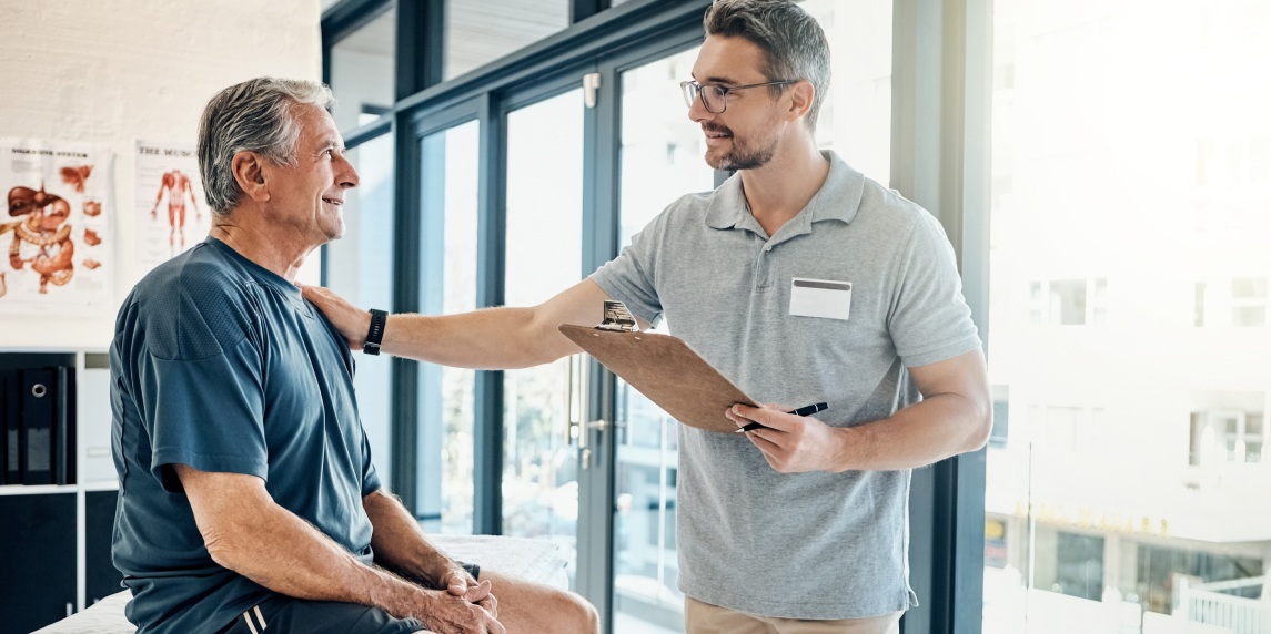 Physical therapy, clipboard and mature man consulting chiropractor at clinic for body, assessment and examination. Physiotherapy, service and client with expert for insurance, checklist or compliance