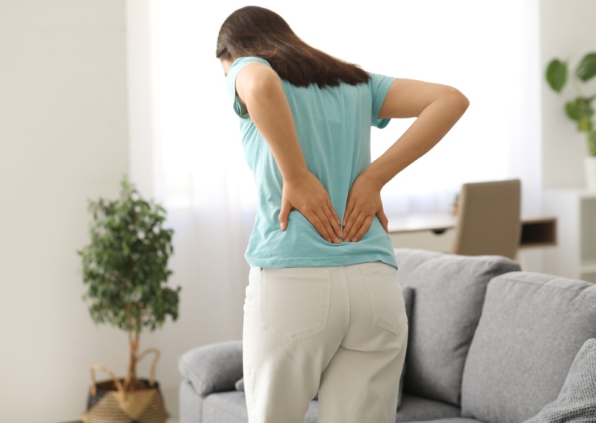 Young woman suffering from back pain at home