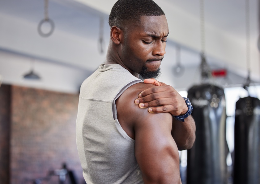 Exercise, black man and shoulder pain for training, fitness and workout for wellness in gym. Nigerian male, athlete and body care with pain, tired and injury for ache, strong and orthopedic problem