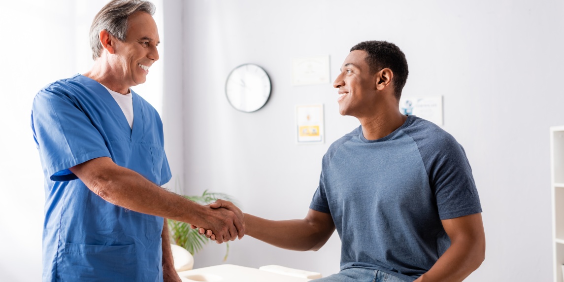 happy chiropractor shaking hands with african american patient