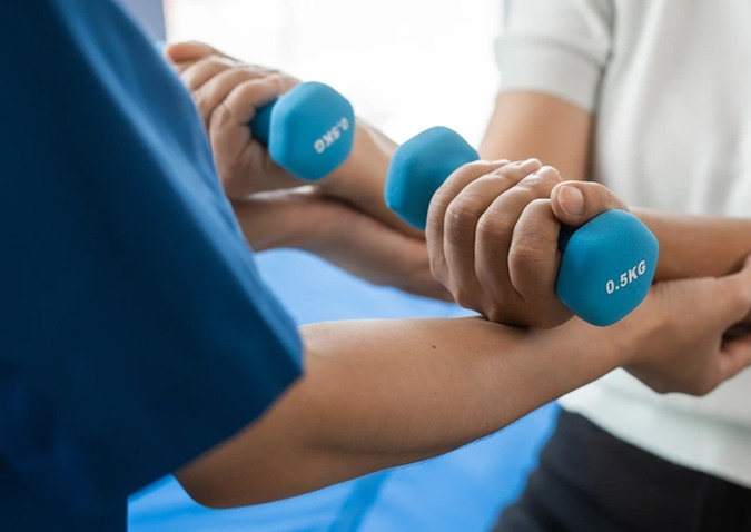 Functional Movement in Santa Monica: A man lifts two blue dumbbells while receiving guidance from a functional movement expert.